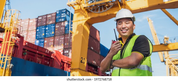Portrait Photo Of Happy Asian Logistics Worker With Radio Transceiver Working In Port Shipping Containers. Logistics, Sea Transportation,  Commercial And Logistics Business Concept