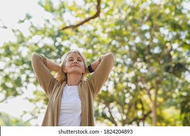 Porträtfoto von glücklicher Seniorin Kaukasierin entspannend und atmen frische Luft mit Sonnenlicht im Außenpark. Ältere Frau genießt im Sommer einen Tag im Park. Lebensstil und Wellness im Gesundheitswesen 