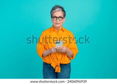 Portrait photo of pensioner business woman using smartphone for corporate communications remotely isolated on cyan color background