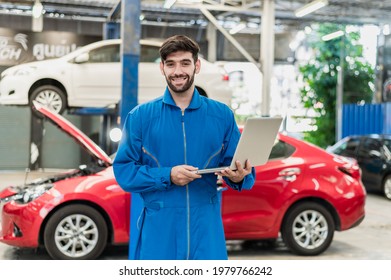 Portrait Photo Of Professional Look Caucasian Vehicle Service Technician Standing Indoor Of Car Repair Shop And Holding Notebook Computer.