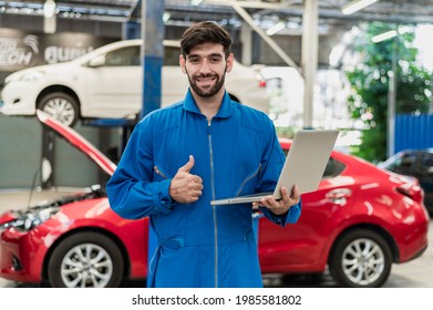 Portrait Photo Of Professional Look Caucasian Vehicle Service Technician Standing Indoor Of Car Repair Shop, Holding Notebook Computer And Showing Thumb-up