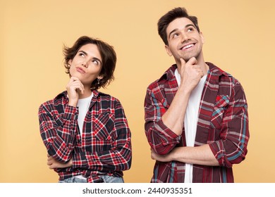 Portrait photo of a thoughtful couple, with a dreaming woman and a smiling man, thinking deeply about an idea, crossing their arms, posing isolated on a yellow background, and looking away - Powered by Shutterstock