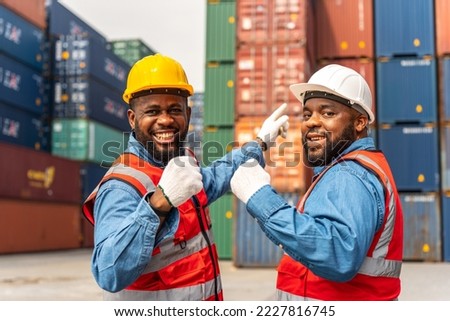 Portrait photo of two black african male container engineers smile as a team after safety inspection work on the containers at a shipping yard of a local logistic freight forwarder company