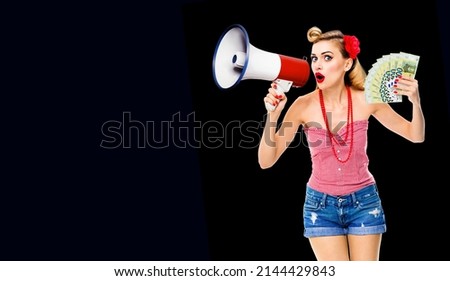 Portrait photo woman holding megaphone and money euro cash banknotes, shout. Blond girl in pin up style, on dark black background. Female model in retro vintage concept.