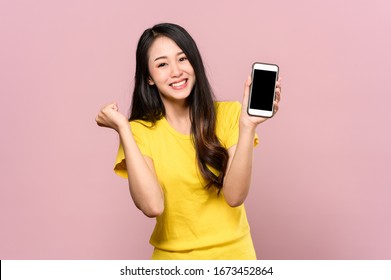 Porträtfoto von jungen schönen asiatischen Frauen fühlen sich glücklich oder Überraschung Schock und halten Smartphone mit schwarzen leeren Bildschirm auf rosafarbenem Hintergrund kann für Werbung oder Produktpräsentation Konzept.