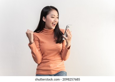 Portrait photo of young beautiful Asian woman feeling happy or surprise shock and looking at smart phone on white background can use for advertising or product presenting concept.