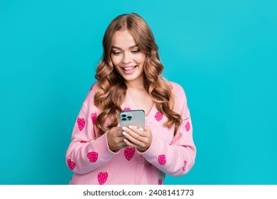 Portrait photo of young excited beautiful funny happy woman using her iphone 15 pro max with three camera isolated on blue color background