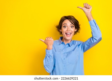Portrait photo of young funny excited girlish woman wear blue shirt crazy fingers pointing empty space good vacancy isolated on yellow color background - Shutterstock ID 2226629221