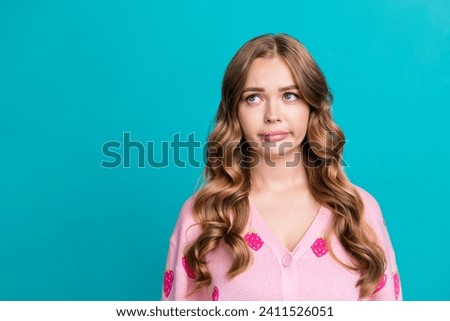 Portrait photo of young funny sad stunning girl grimacing looking empty space in bad mood deciding isolated on blue color background