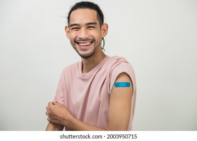 Portrait Foto junge glückliche asiatische Hipster Mann mit bunten Verband Lachen glücklich, nachdem sie covid-19-Impfstoff aus freien Impfkampagnen gegen den Ausbruch von Coronavirus erhalten. Asiatische Menschen porträtieren.