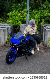 portrait photo of a young hijab woman with a blue motorbike. 10 October 2020. Tanjungpinang, Riau Islands, Indonesia