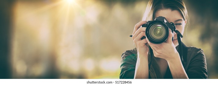 Portrait of a photographer covering her face with the camera.