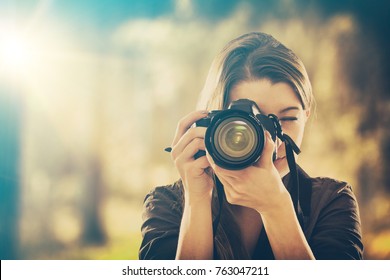Portrait of a photographer covering her face with the camera.