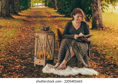 Portrait photography of a woman sitting on an armchair and reading a book while enjoying the colorful autumn atmosphere - Shutterstock ID 2205401665