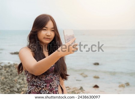Portrait picture of happy Asian young woman with mobile phone on a beach, Thailand.