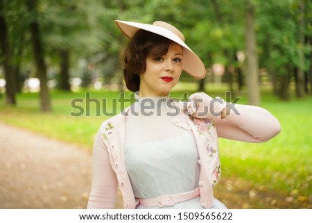 Portrait of pin up young woman in vintage dress and retro hat walking