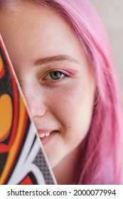 Portrait Of A Pink-haired Teenage Girl Covering Half Of Her Face With A Skateboard.Generation Z Style, Summer Concept.