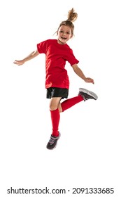 Portrait of playful little girl in red sportive uniform training, playing football isolated over white background. Concept of action, sportive lifestyle, team game, health, energy, vitality and ad
