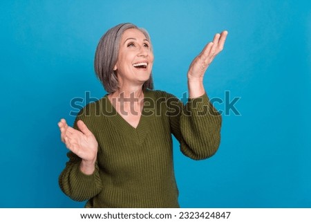 Portrait of pleasant good mood person with gray hairdo wear knit pullover look at offer empty space isolated on blue color background