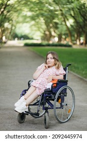 Portrait of pleasant young woman with spinal muscular atrophy smiling on camera among green summer park. Female person who using wheelchair. Concept of people with disability. - Shutterstock ID 2092445974