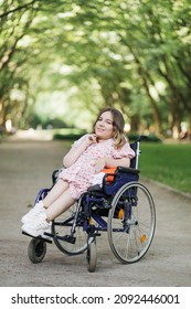 Portrait of pleasant young woman with spinal muscular atrophy smiling on camera among green summer park. Female person who using wheelchair. Concept of people with disability. - Shutterstock ID 2092446001