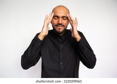 Portrait Of Pleased Young Man Rubbing Temples. Peaceful Multiethnic Male Model With Bald Head And Beard In Black Shirt With Closed Eyes Massaging Head. Headache, Massage Concept