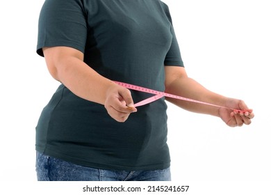 Portrait of a plump girl wearing a gray t-shirt uses the tape measure at the waist to check her proportions on a white background. Selective focus. - Shutterstock ID 2145241657