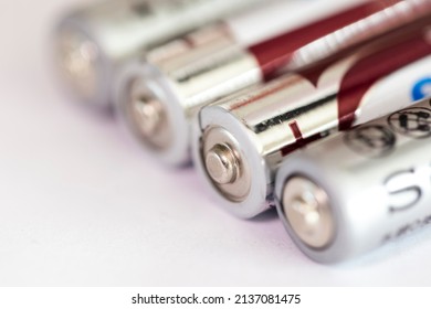 A Portrait Of The Plus Or Positive Side Of A Couple Of Triple A Or AAA Batteries Lying On An Almost White Surface.