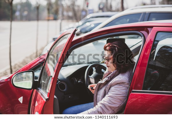 Portrait of plus size woman in red car on city
street . Woman driver concept. Mature women lifestyle. Model plus
size . XXL model
