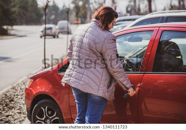 Portrait of plus size woman in red car on city\
street . Woman driver concept. Mature women lifestyle. Model plus\
size . XXL model
