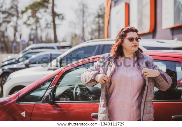 Portrait of plus size woman in red car on city
street . Woman driver concept. Mature women lifestyle. Model plus
size . XXL model