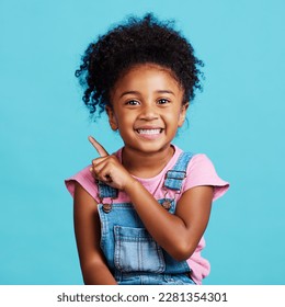 Portrait  pointing   mockup and girl blue background in studio showing product placement space  Kids  marketing   advertising and an adorable female child indoor to point at branding