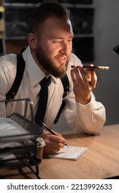 Portrait Of A Police Officer Or Investigator Working In The Office At The Table Dictating Information On The Phone, Smartphone Voice Assistant For Work