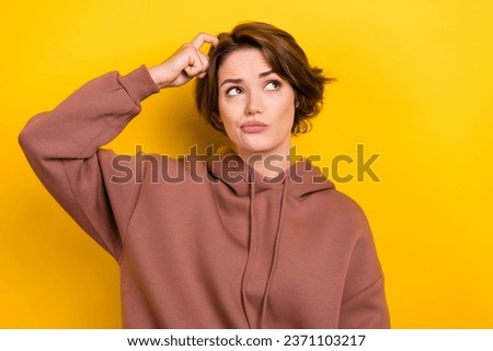 Portrait of ponder pensive girl bob hair dressed brown sportswear scratches her head look empty space isolated on yellow color background