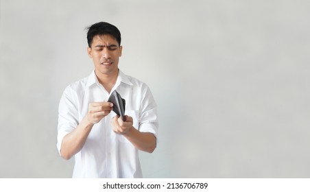 Portrait of poor Asian guy unhappy, worried, lose money, funny facial expressions with the empty wallet. Concept of employee, businessman, office worker, bankruptcy, and unemployment in economy crisis - Shutterstock ID 2136706789