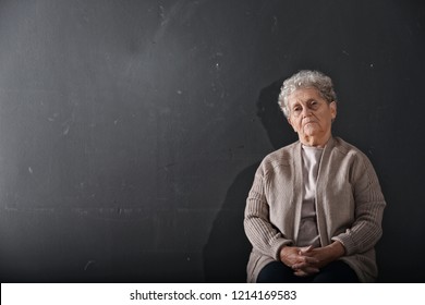 Portrait Of Poor Elderly Woman On Dark Background. Space For Text