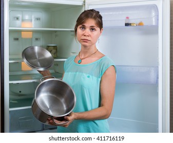 Portrait Of Poor Girl Near Empty Fridge