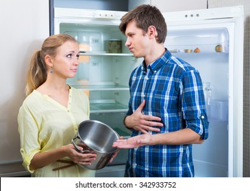 Portrait Of Poor And Hungry American Couple Near Empty Fridge