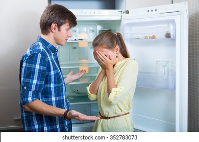 Portrait Of Poor And Hungry Couple Near Empty Fridge