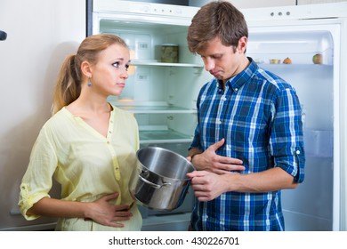 Portrait Of Poor And Hungry Family Near Empty Fridge