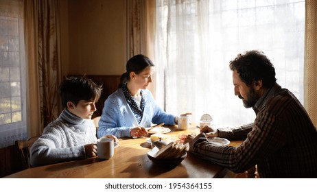 Portrait Of Poor Sad Small Girl With Parents Eating Indoors At Home, Poverty Concept.