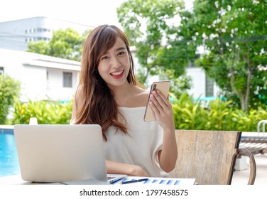 Portrait portraits of beautiful and pretty Asian women playing on mobile phones to use mobile applications. And surf the internet On her vacations by the pool - Shutterstock ID 1797458575