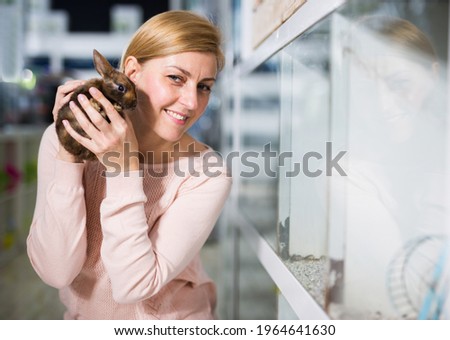 Portrait of positive american woman shopper looking for bunny in pet store