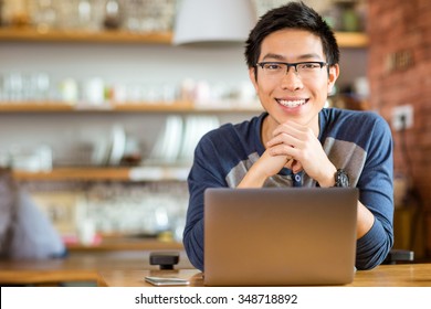 Portrait Of Positive Asian Male In Glasses With Laptop In Cafe