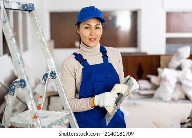 Portrait Of Positive Asian Woman Builder With Float Trowel Standing In Apartment.