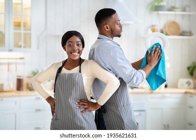 Portrait of positive black woman and her husband wiping dishes at kitchen - Powered by Shutterstock