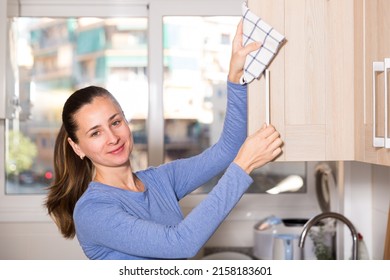 Portrait Of Positive Brunette Woman Cleaning Kitchen With Rag