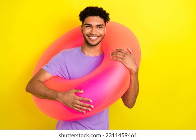 Portrait of positive carefree young man toothy smile hold inflatable ring enjoy summertime isolated on yellow color background - Shutterstock ID 2311459461