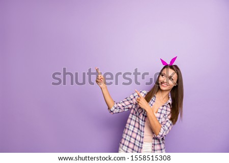 Portrait of positive cheerful girl point index finger copyspace recommend ads promotion wear casual style retro outfit isolated over purple color background