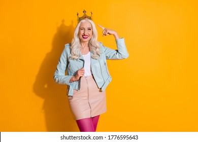 Portrait Of Positive Cheerful Old Woman Demonstrate Her Party Win Point Index Finger Golden Crown Wink Blink Wear Good Look Pink Stockings Isolated Over Bright Shine Color Background